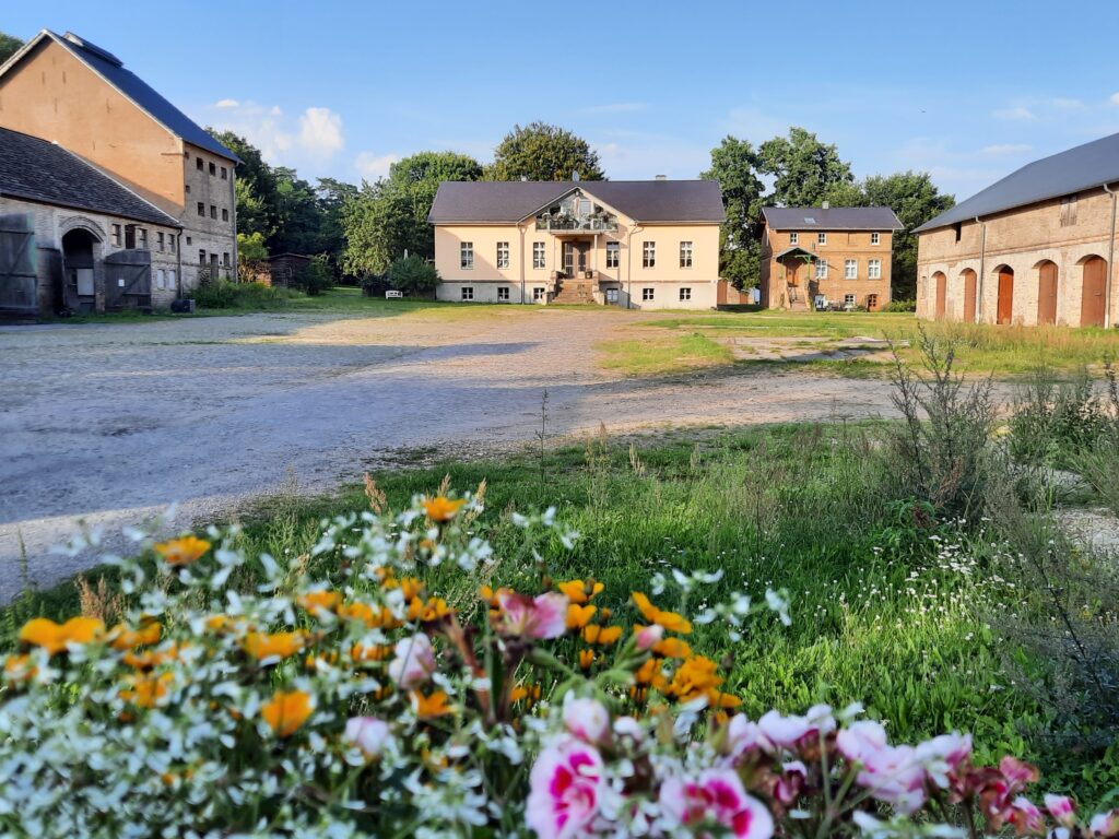 Gebäude von Gut Lanke. Im Vordergrund Sommerblumen.